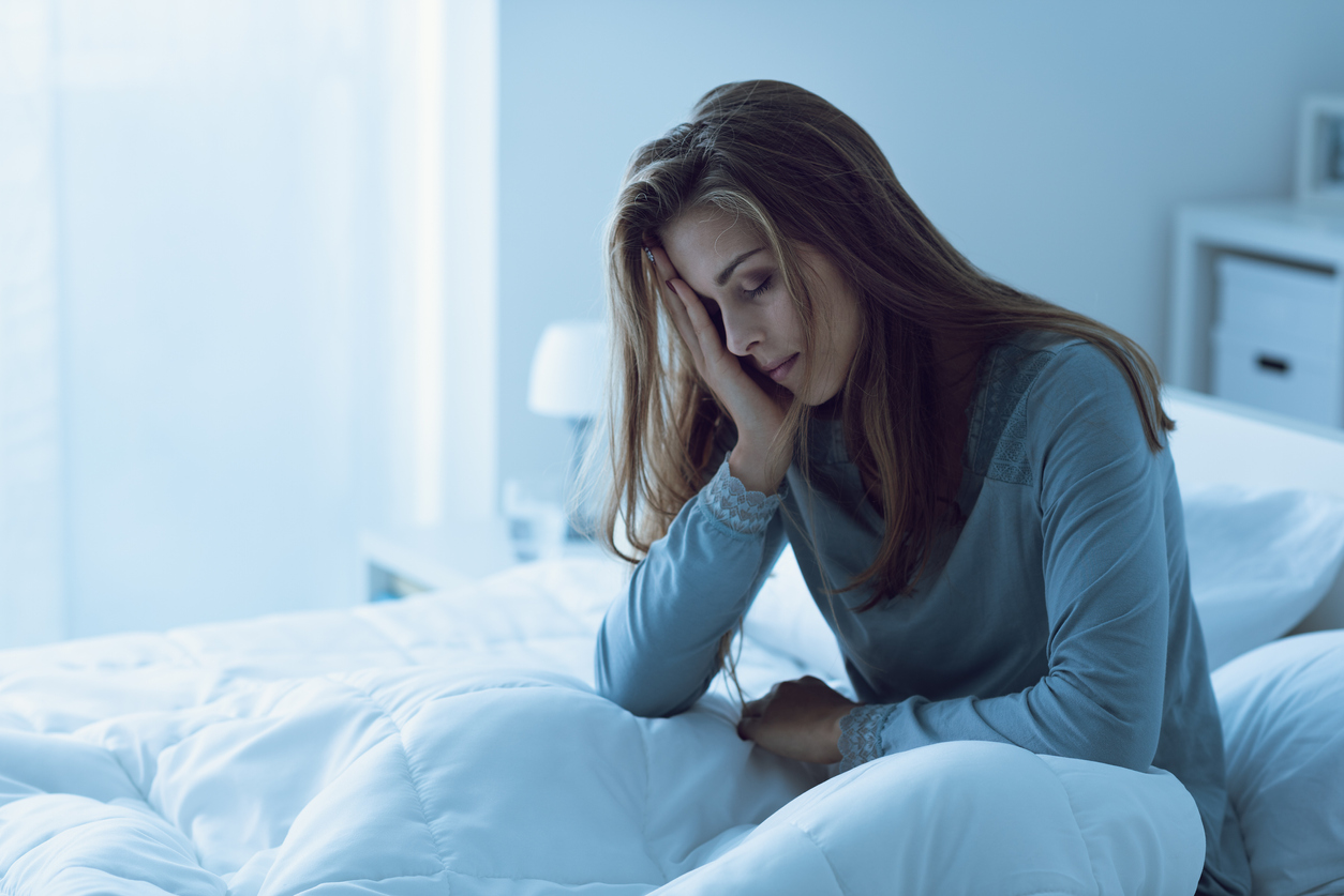 Teen awake in the night, she is touching her forehead and suffering from insomnia